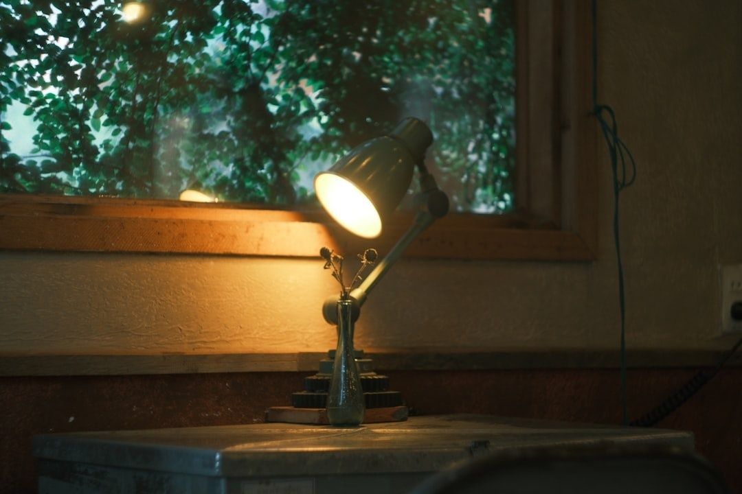 Tänd skrivbordslampa lyser upp en arbetsplats vid ett fönster