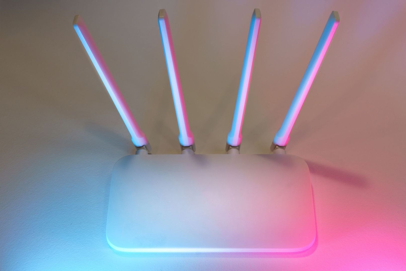 Vit trådlös router med fyra upplysta antenner i blått och rosa