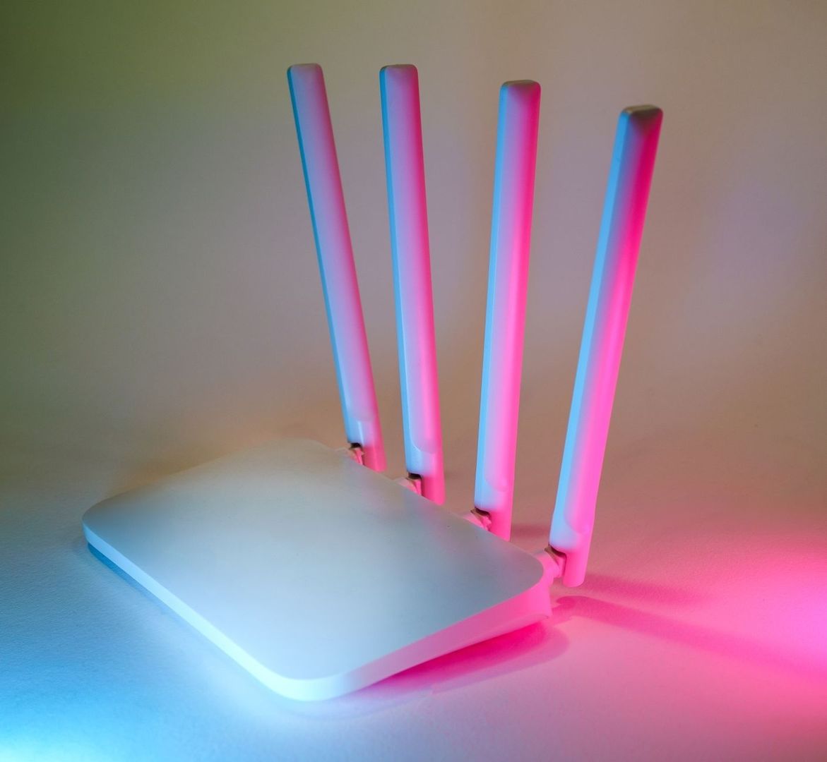 Vit Wi-Fi-router med fyra antenner i blått och rosa ljus