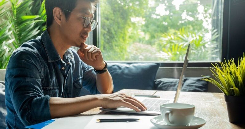 Frilansare arbetar vid laptop med kaffe och anteckningsblock